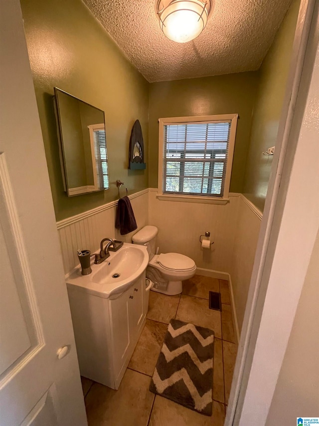 bathroom featuring tile patterned floors, a textured ceiling, vanity, and toilet