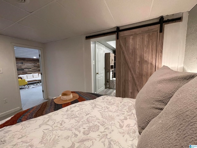 bedroom featuring light carpet and a barn door