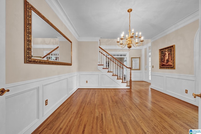 foyer entrance featuring light hardwood / wood-style floors, crown molding, and an inviting chandelier