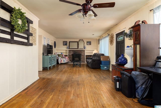 living room featuring hardwood / wood-style flooring, a wealth of natural light, ornamental molding, and a fireplace