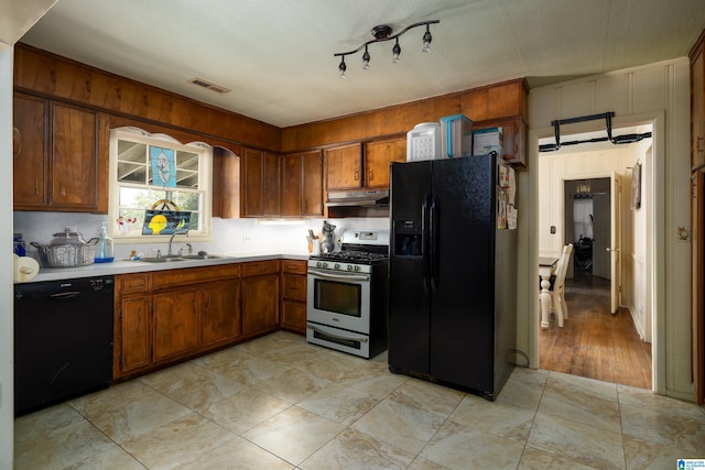 kitchen featuring light tile patterned floors, sink, black appliances, and a textured ceiling