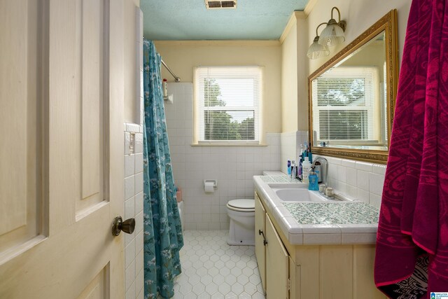 bathroom with toilet, tile walls, a textured ceiling, vanity, and tile patterned flooring