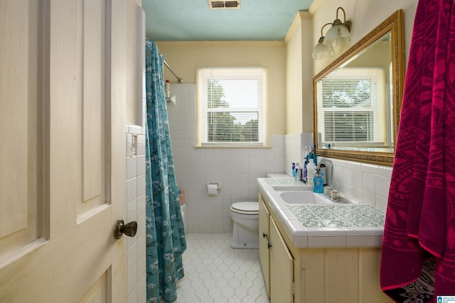 bathroom with tile walls, vanity, a textured ceiling, tile patterned flooring, and toilet