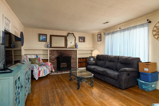 living room featuring ornamental molding, a brick fireplace, and wood-type flooring