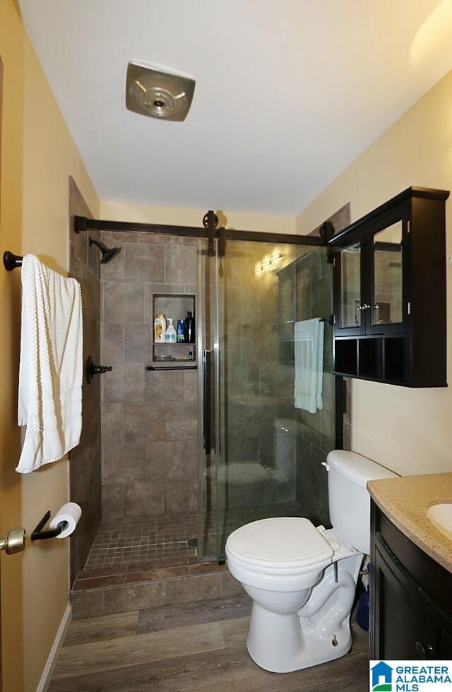 bathroom featuring vanity, toilet, hardwood / wood-style floors, and a shower with door