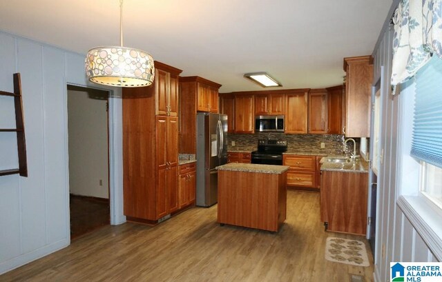 kitchen with a kitchen island, light wood-type flooring, sink, and appliances with stainless steel finishes