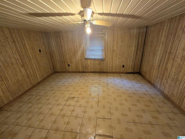 additional living space with wood walls, ceiling fan, and light tile patterned floors