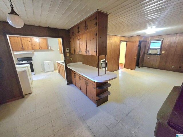 kitchen featuring white range, pendant lighting, and wooden walls