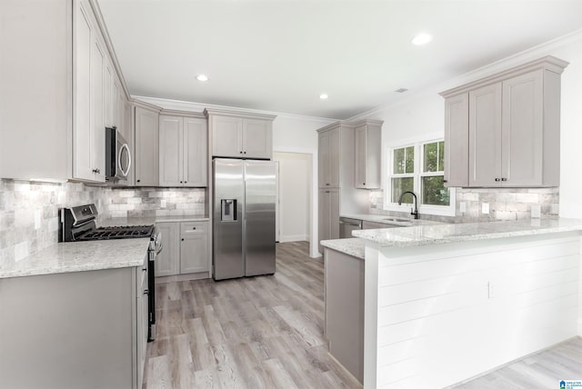 kitchen with light stone counters, light wood-type flooring, kitchen peninsula, and stainless steel appliances