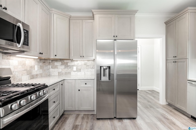 kitchen with appliances with stainless steel finishes, light stone counters, decorative backsplash, light wood-type flooring, and crown molding