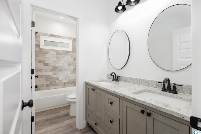 full bathroom featuring tiled shower / bath combo, toilet, wood-type flooring, and double sink vanity