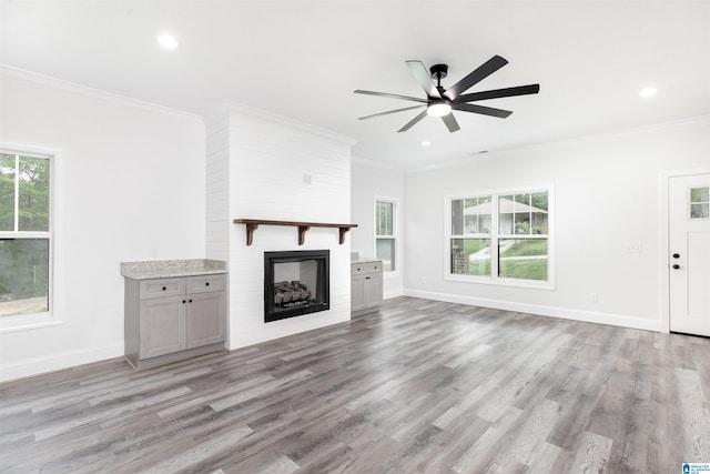 unfurnished living room with a fireplace, ceiling fan, hardwood / wood-style floors, and crown molding