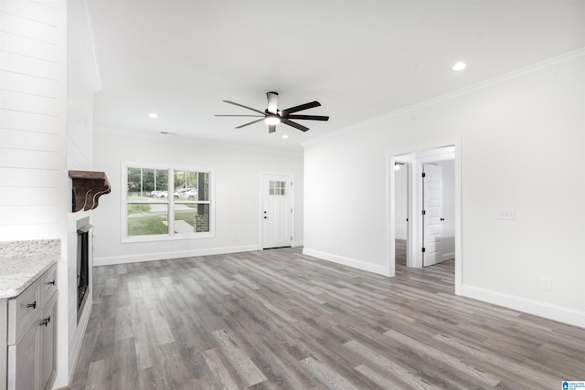 unfurnished living room with a large fireplace, ceiling fan, light wood-type flooring, and crown molding