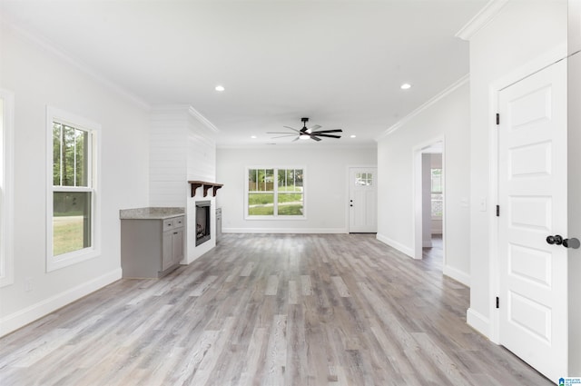 unfurnished living room with light hardwood / wood-style floors, ornamental molding, a fireplace, and ceiling fan