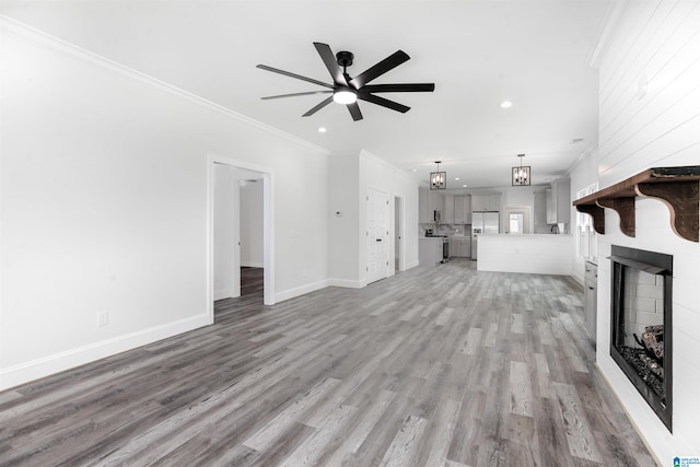 unfurnished living room with a fireplace, ceiling fan, light wood-type flooring, and crown molding