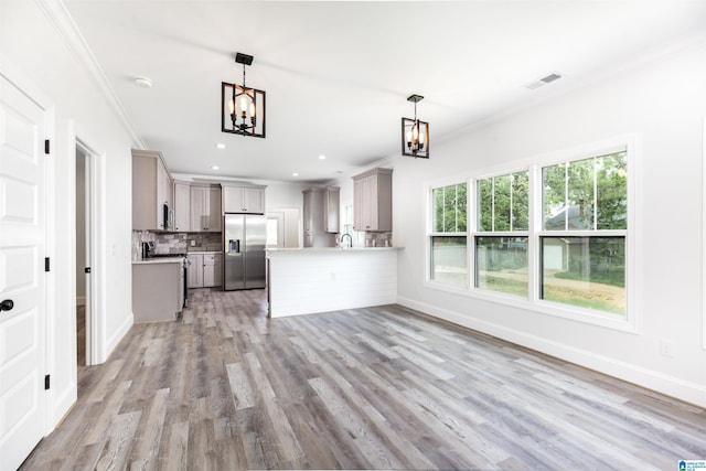 kitchen featuring kitchen peninsula, decorative backsplash, light wood-type flooring, stainless steel refrigerator with ice dispenser, and a chandelier