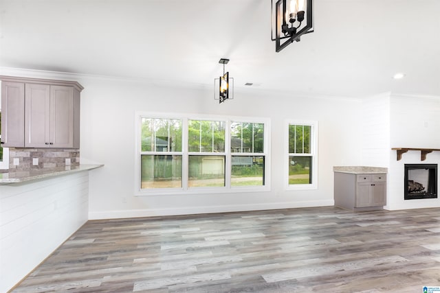 unfurnished living room featuring hardwood / wood-style flooring, a wealth of natural light, and an inviting chandelier