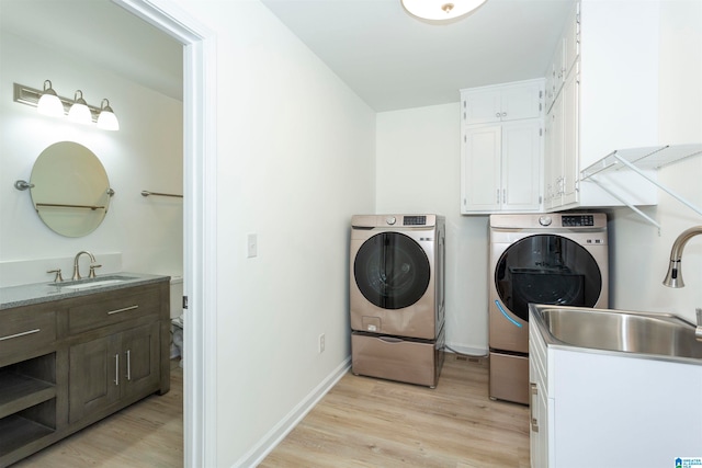 washroom with separate washer and dryer, light hardwood / wood-style flooring, sink, and cabinets