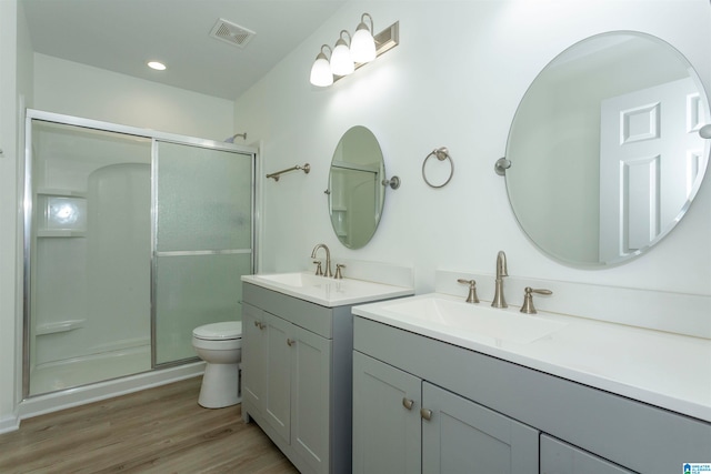 bathroom with vanity, toilet, a shower with door, and hardwood / wood-style floors