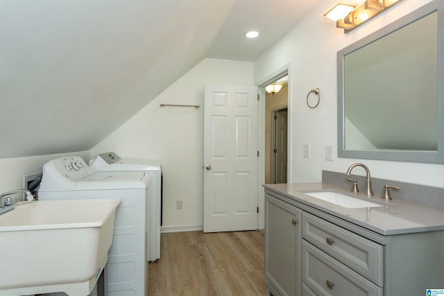 laundry area with light hardwood / wood-style floors, washer and dryer, and sink