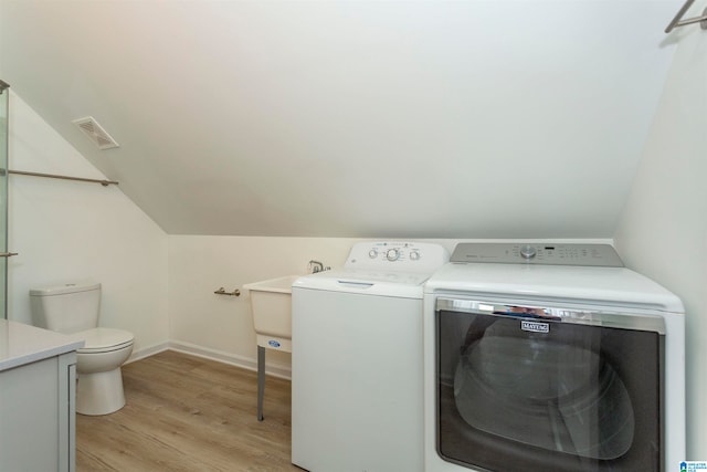 clothes washing area with washer and dryer and light wood-type flooring