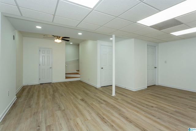 basement with ceiling fan, a drop ceiling, and light hardwood / wood-style floors