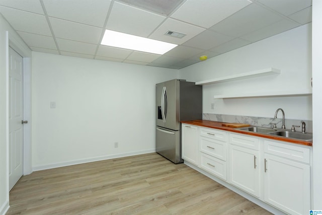 kitchen with a drop ceiling, light hardwood / wood-style flooring, stainless steel fridge with ice dispenser, and sink