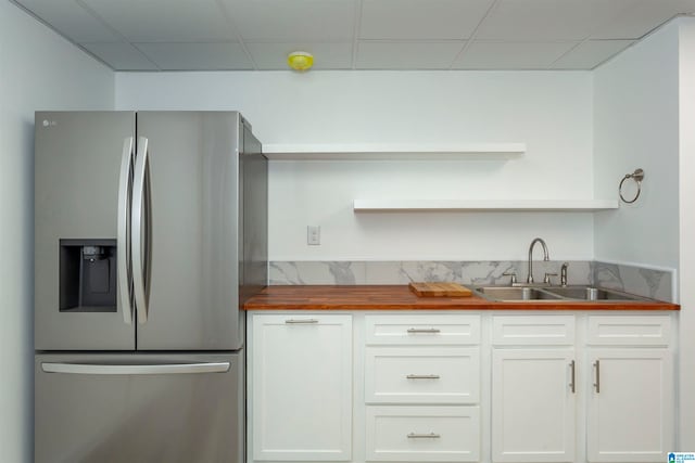 kitchen with wood counters, white cabinets, sink, a drop ceiling, and stainless steel refrigerator with ice dispenser