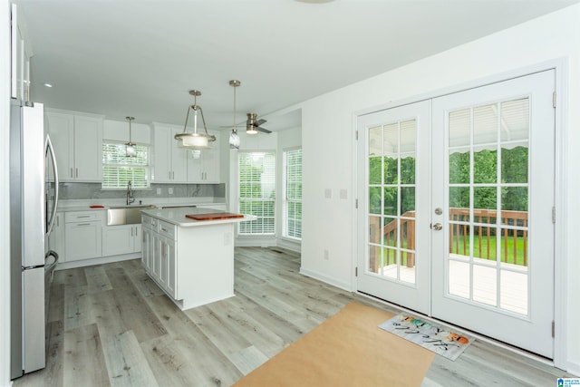 kitchen featuring white cabinetry, a center island, stainless steel fridge, and light hardwood / wood-style floors