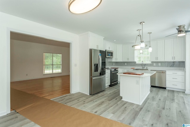 kitchen featuring stainless steel appliances, a kitchen island, light wood-type flooring, and plenty of natural light