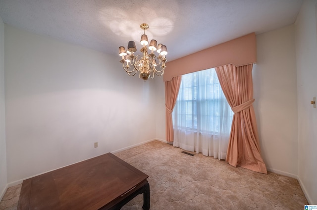 empty room with a textured ceiling and a chandelier