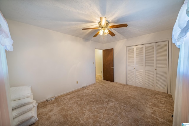 unfurnished bedroom with a textured ceiling, ceiling fan, and a closet