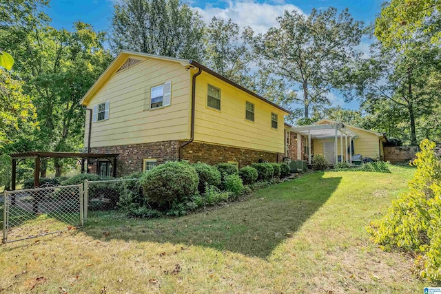 view of side of property featuring brick siding, fence, and a yard