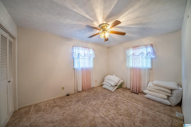 unfurnished bedroom featuring multiple windows, ceiling fan, a closet, and a textured ceiling