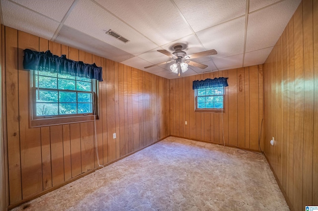 empty room featuring ceiling fan and wooden walls