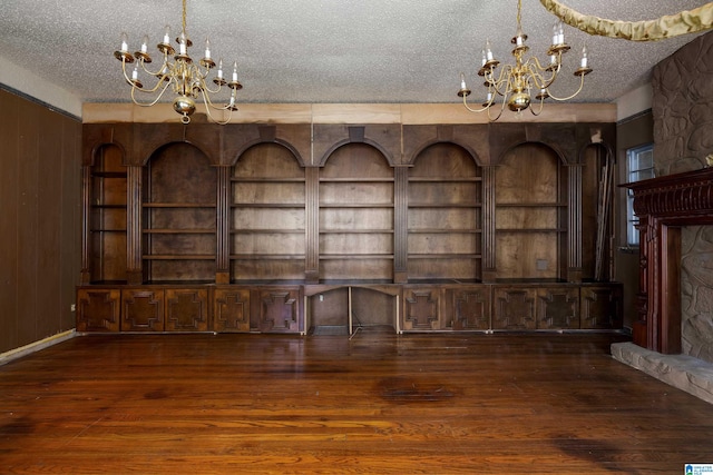 unfurnished living room with built in shelves, a textured ceiling, and hardwood / wood-style floors