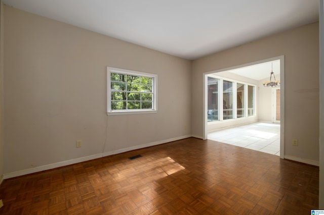 spare room with an inviting chandelier and parquet floors