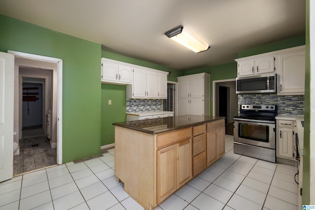 kitchen with light tile patterned floors, a center island, white cabinets, and stainless steel appliances