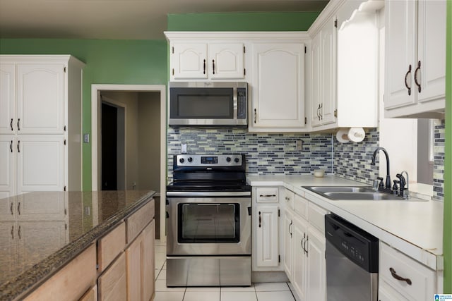 kitchen featuring dark stone counters, white cabinetry, light tile patterned flooring, sink, and appliances with stainless steel finishes