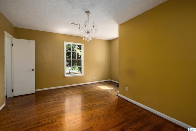 unfurnished room with a textured ceiling, an inviting chandelier, and wood-type flooring