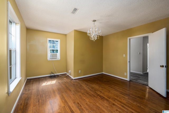 unfurnished room featuring a textured ceiling, hardwood / wood-style floors, and a chandelier