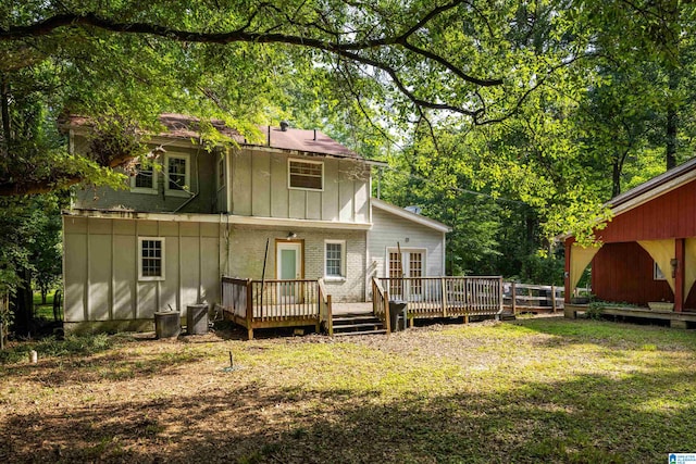 rear view of house featuring a wooden deck and a lawn