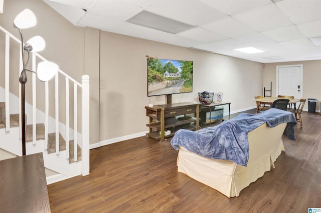 living room with dark hardwood / wood-style flooring and a drop ceiling