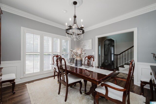 dining area with dark wood-type flooring, crown molding, and a chandelier