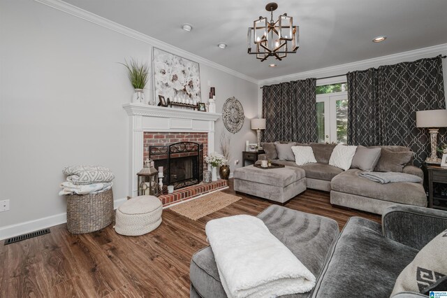 living room featuring crown molding, dark hardwood / wood-style floors, a brick fireplace, and an inviting chandelier