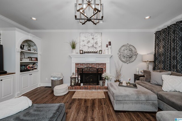 living room featuring a fireplace, crown molding, dark hardwood / wood-style floors, built in shelves, and a chandelier