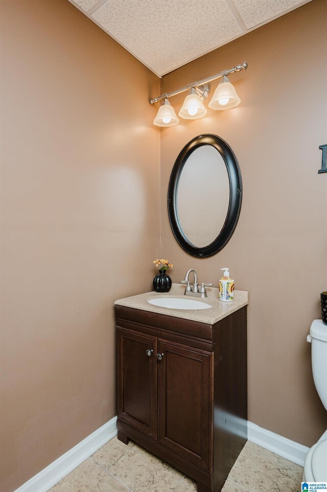 bathroom featuring tile patterned floors, toilet, vanity, and a paneled ceiling