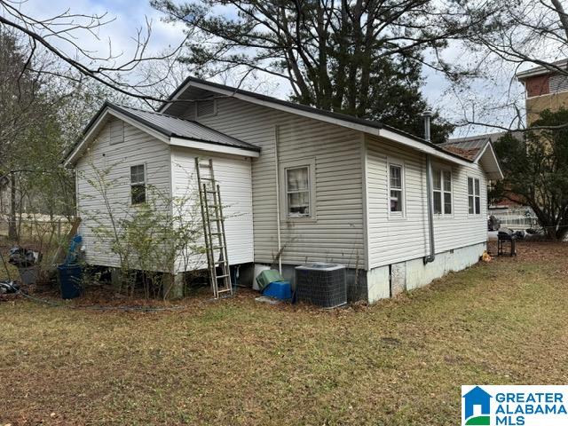 rear view of property with central air condition unit and a yard