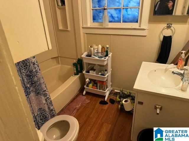 full bathroom featuring vanity, shower / bath combo with shower curtain, hardwood / wood-style flooring, and toilet