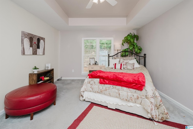 carpeted bedroom with a raised ceiling and ceiling fan